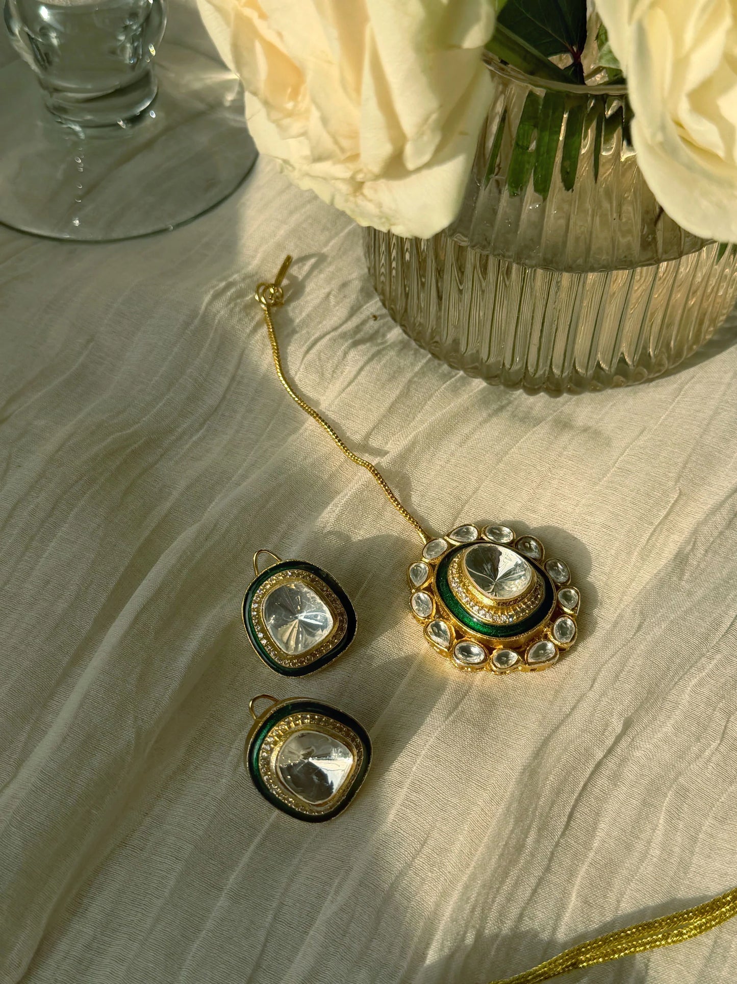 Close-up of ornate gold choker necklace with green enamel and crystal stones on display bust