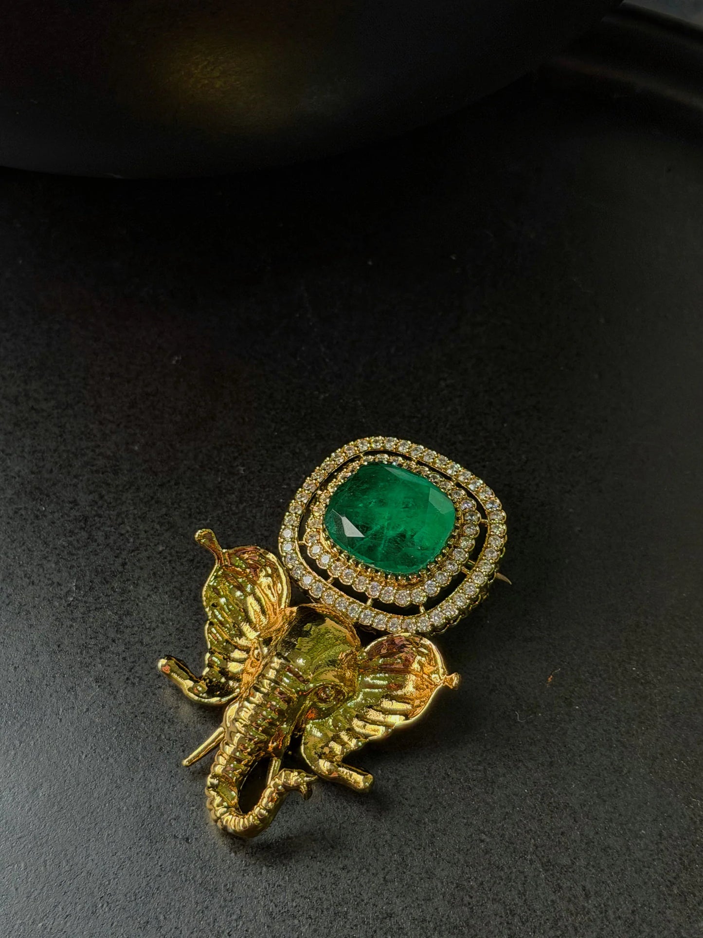 Elegant elephant-shaped gold jewelry with emerald centerpiece and sparkling stones