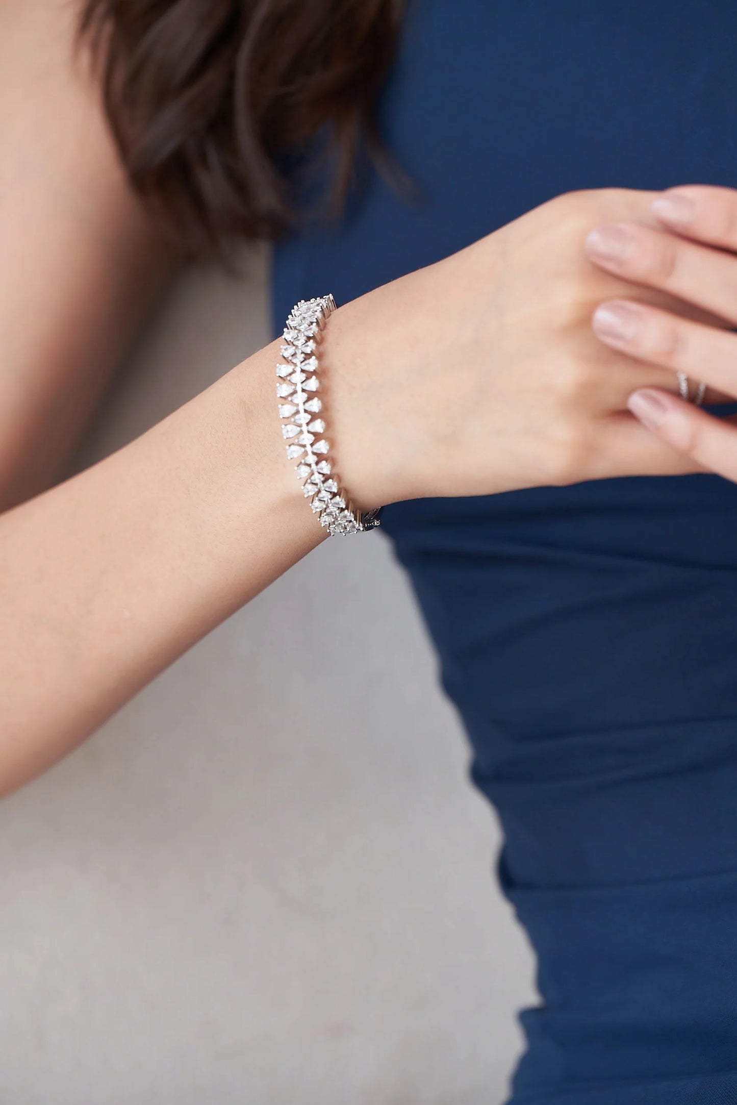 White gold diamond bracelet with alternating pear-shaped stones forming a symmetrical leaf motif on wrist.