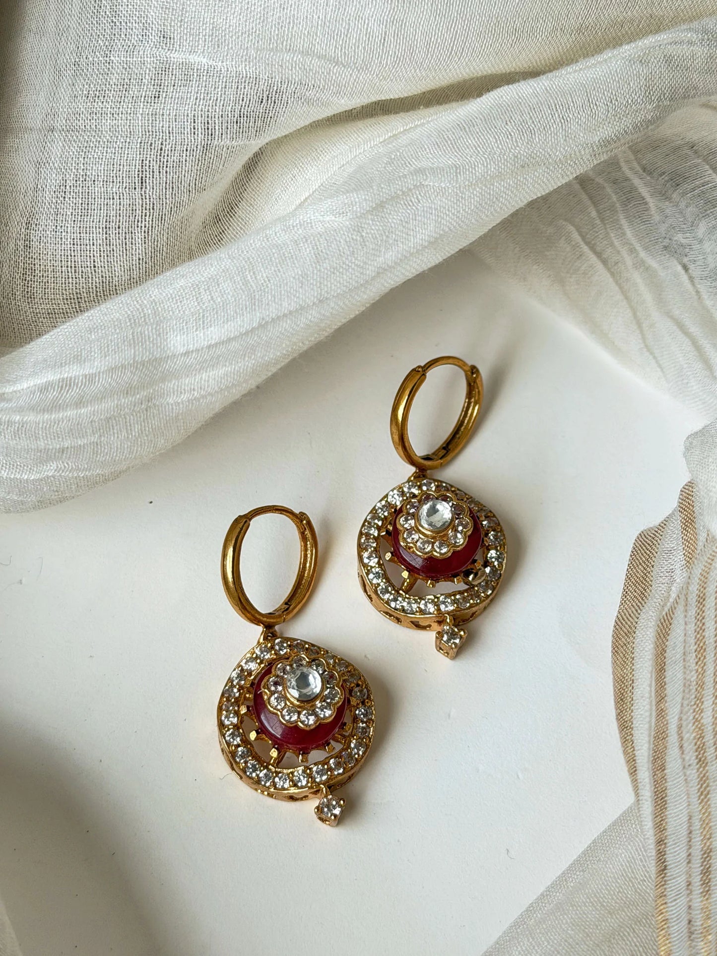Luxury gold hoop earrings with red enamel detailing and sparkling crystal accents in minimal jewelry styling