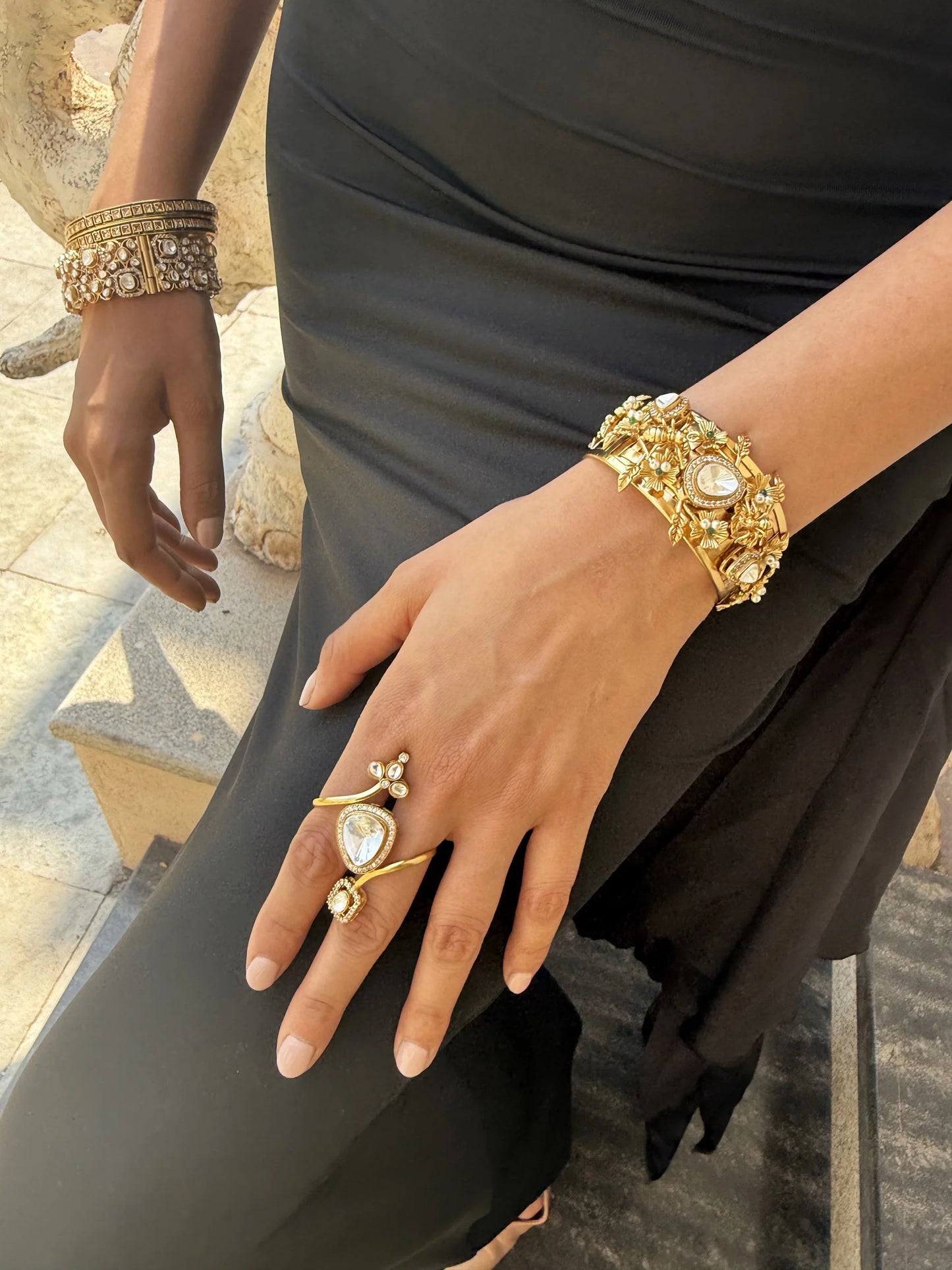 Close-up of an embellished gold bangle paired with bright marigold flowers in a cultural setting
