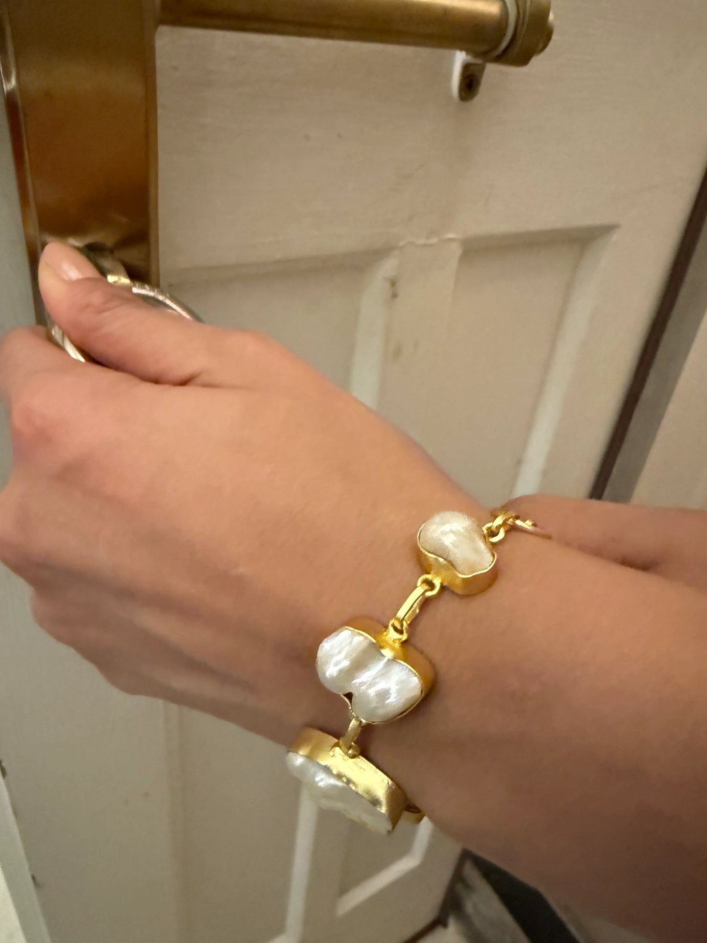 Stylish gold and pearl bracelet on wrist with minimal background highlighting jewelry details