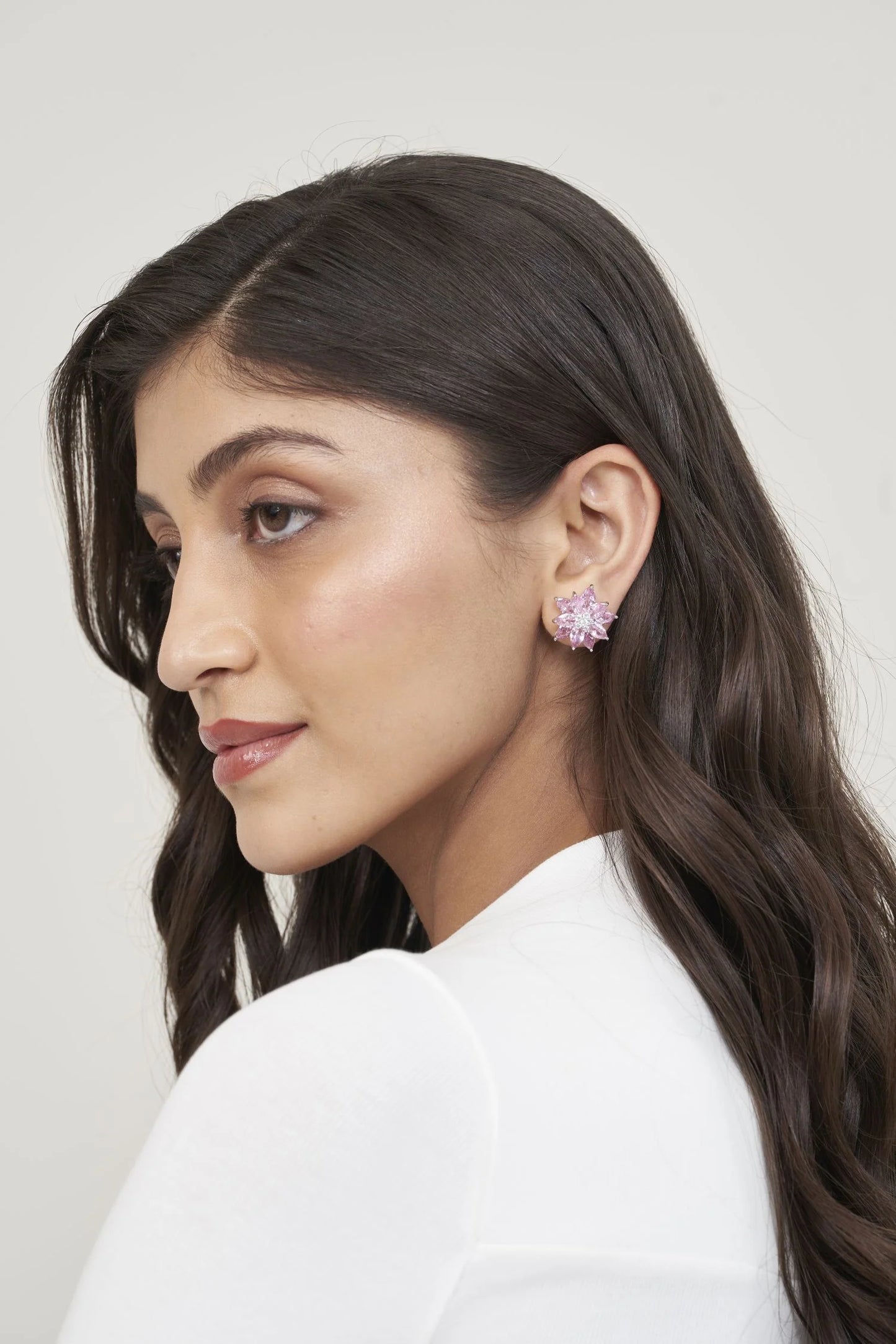 Elegant beauty shot highlighting a floral star-shaped pink gemstone earring with layered sparkling stones on the ear.