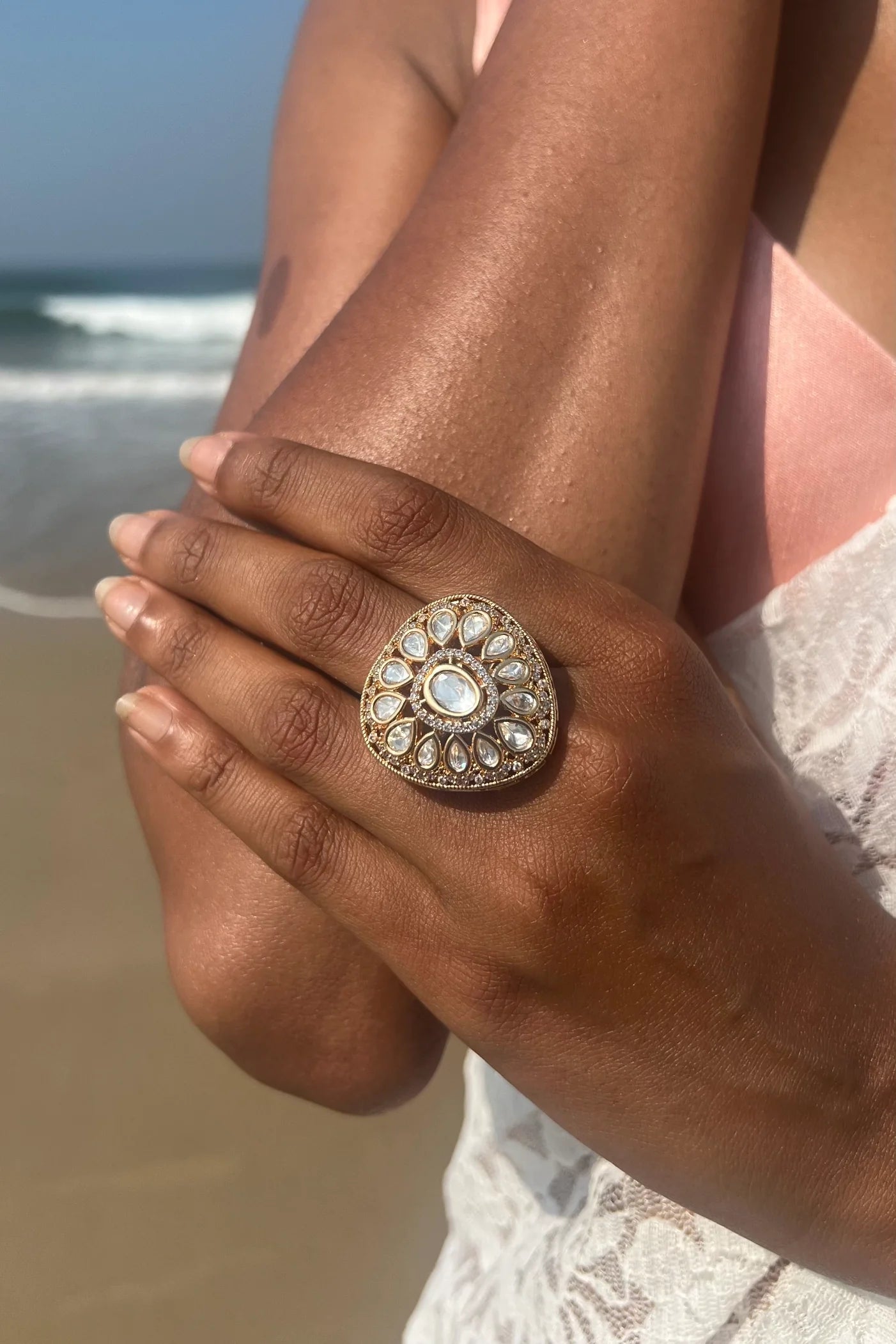 Fine jewelry composition showcasing a statement ring with intricate stone placement forming a sunburst-inspired design on the finger.