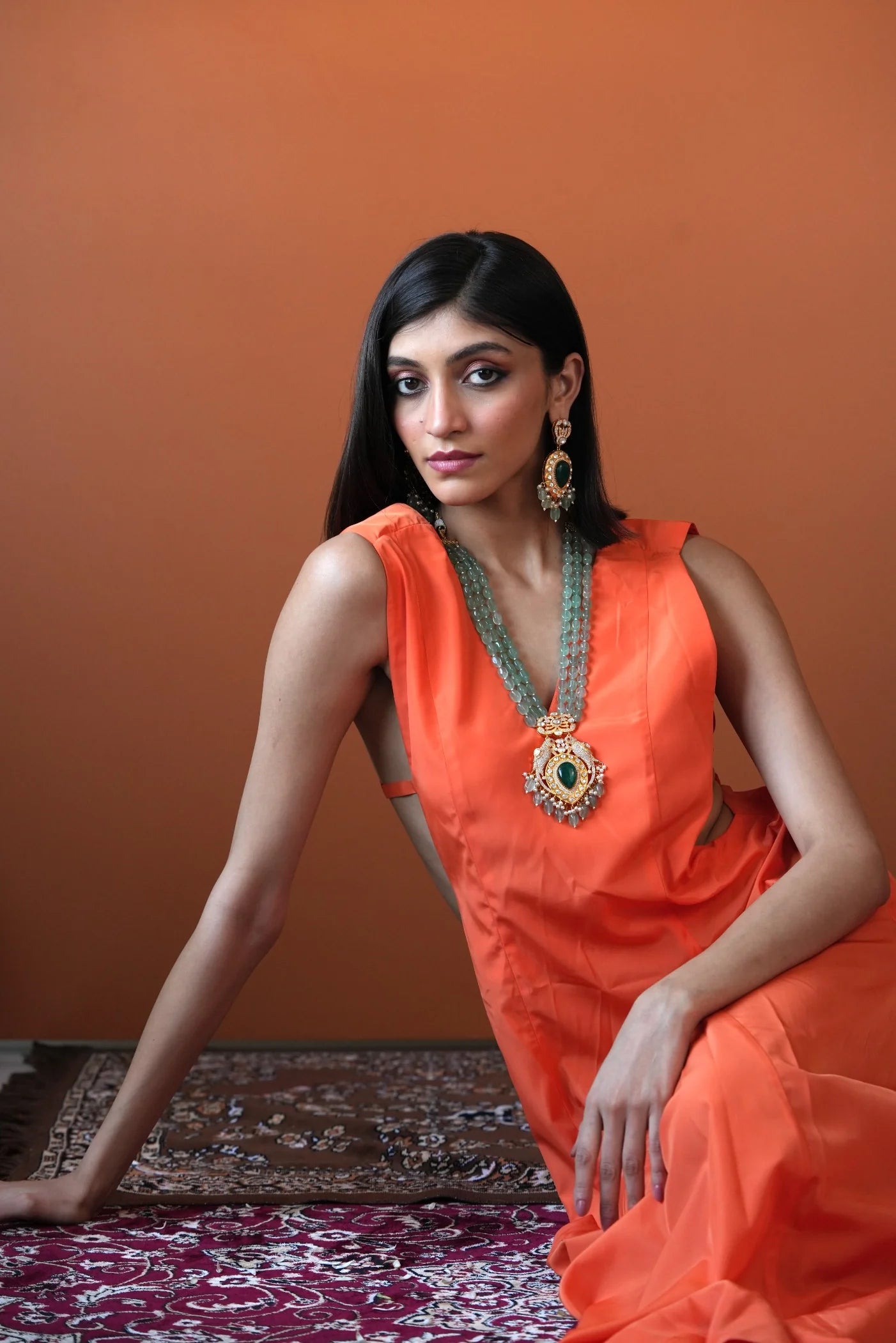 Sophisticated jewelry styling featuring a woman in a bright yellow outfit highlighting a bold green pendant necklace with layered detailing.