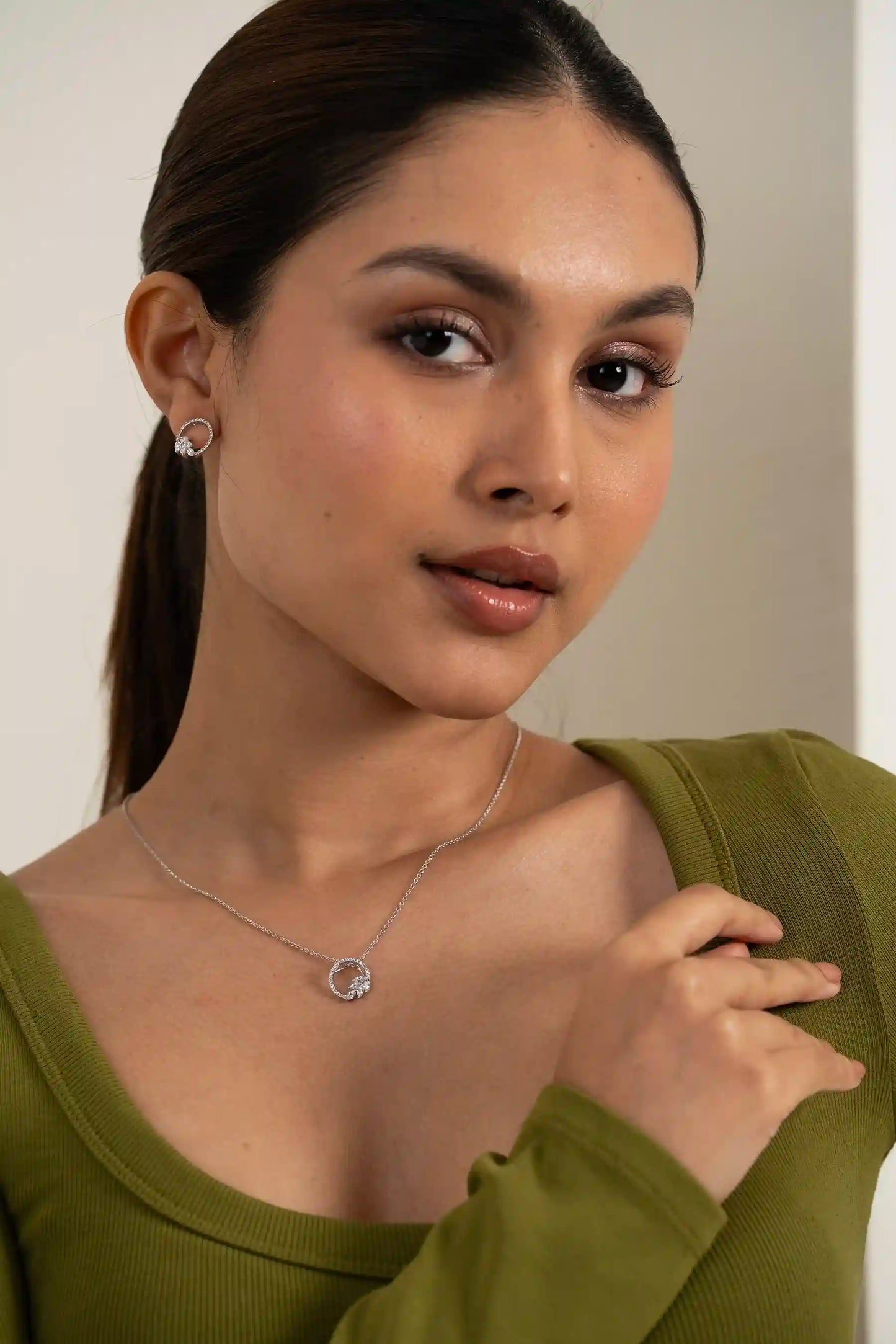 Modern diamond circle pendant and stud earrings styled on model with clean, premium finish