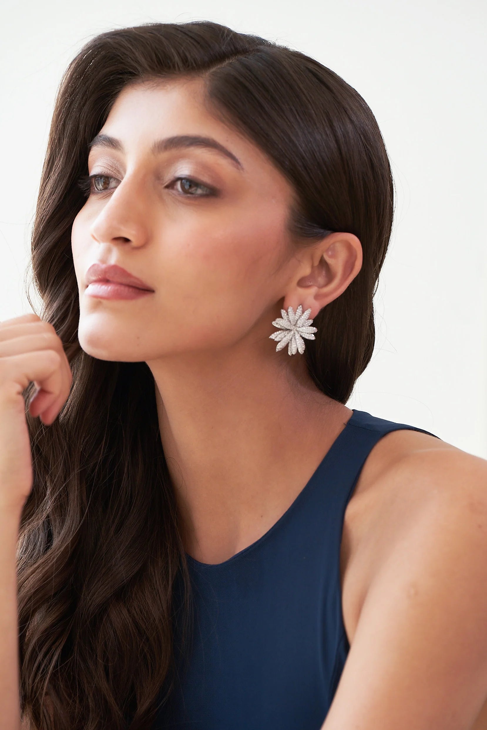 Detailed view of a silver floral earring with layered petal shapes, each covered in shimmering crystals.
