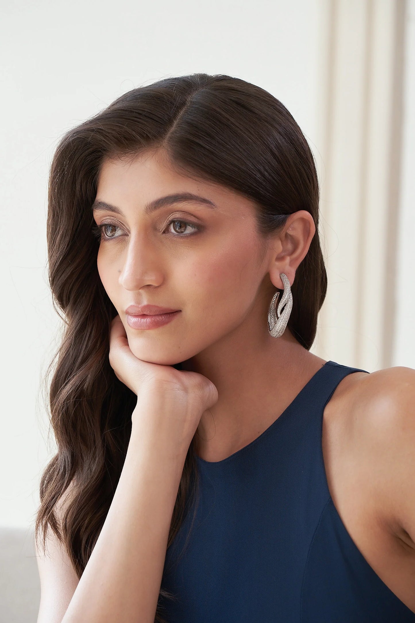 Artistic silver drop earring with a flowing, layered shape and densely set sparkling stones, shown in close detail.
