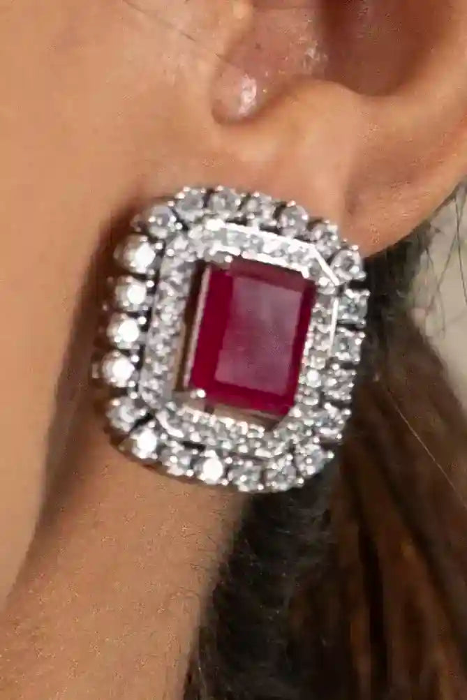 Close-up of cushion-cut ruby pendant necklace with double diamond halo setting on minimal skin background