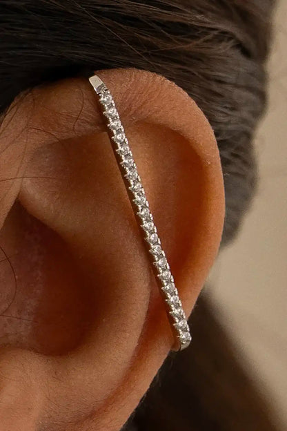 Close-up of a human ear wearing a diamond-studded silver ear cuff, showcasing modern minimalist jewelry design