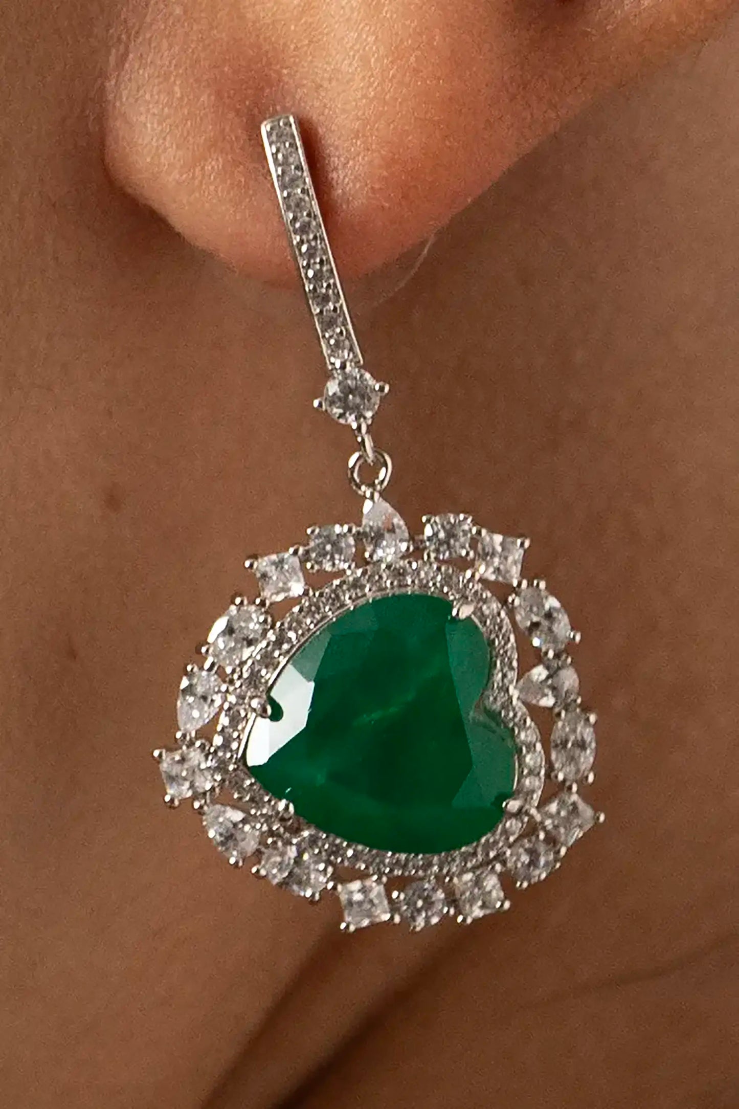 Side angle of a luxury emerald drop earring with a heart-cut green gemstone and sparkling diamond halo.