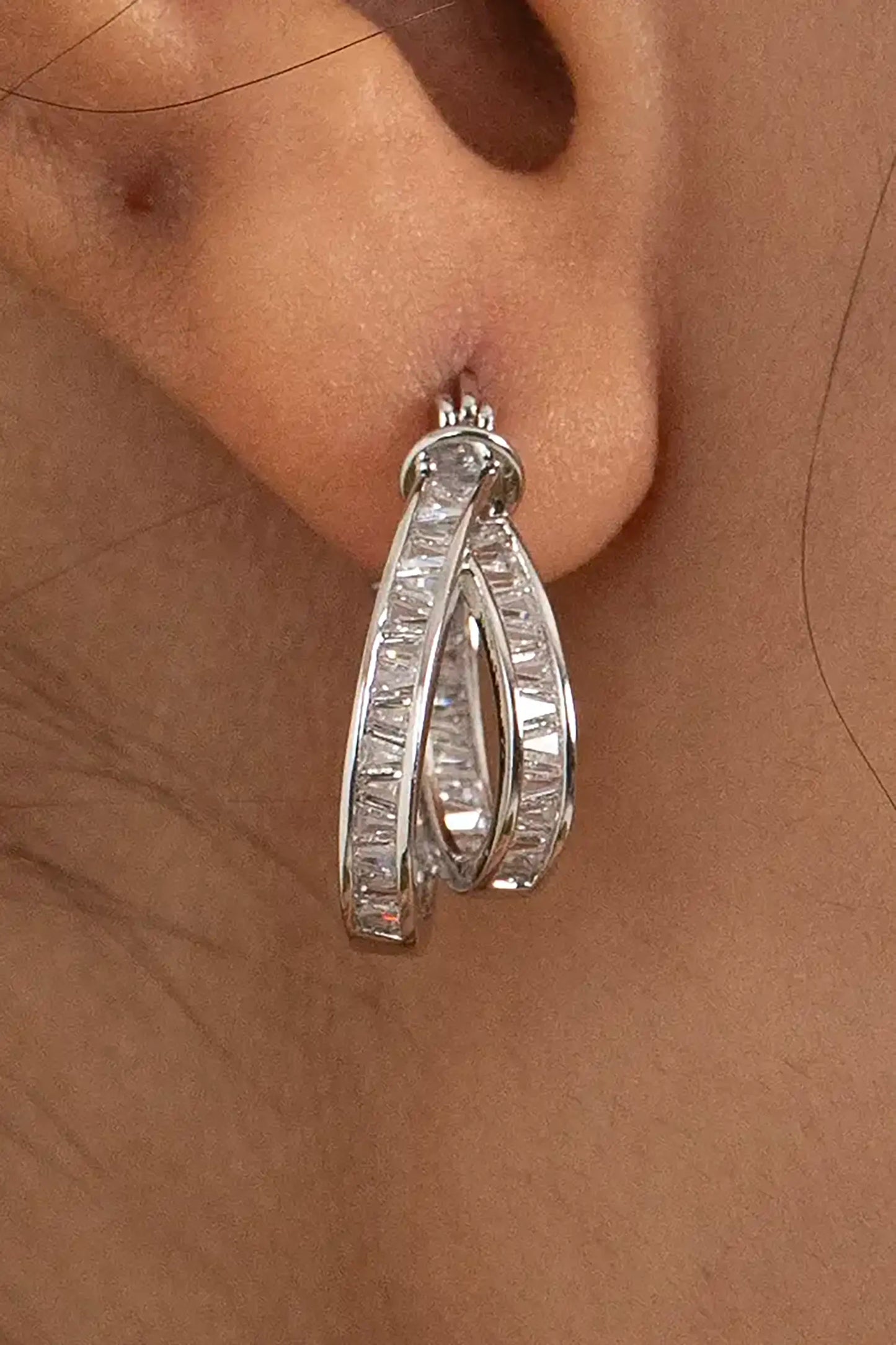Silver hoop earring with baguette-cut diamonds on ear, showcasing modern luxury jewelry style
