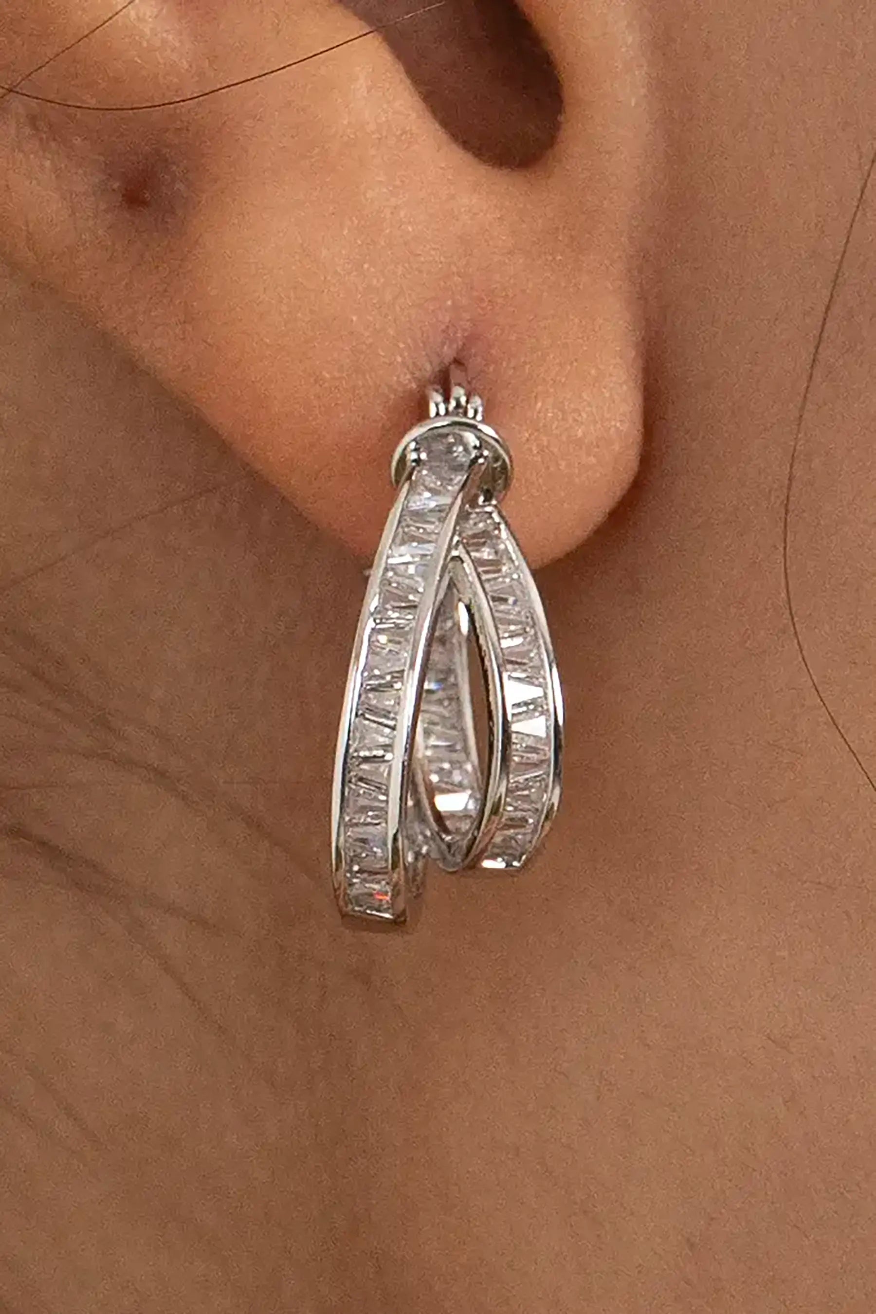 Silver hoop earring with baguette-cut diamonds on ear, showcasing modern luxury jewelry style
