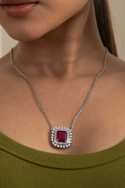 Ruby cushion halo necklace set with square-cut ruby pendant and matching diamond halo earrings on model in olive green outfit