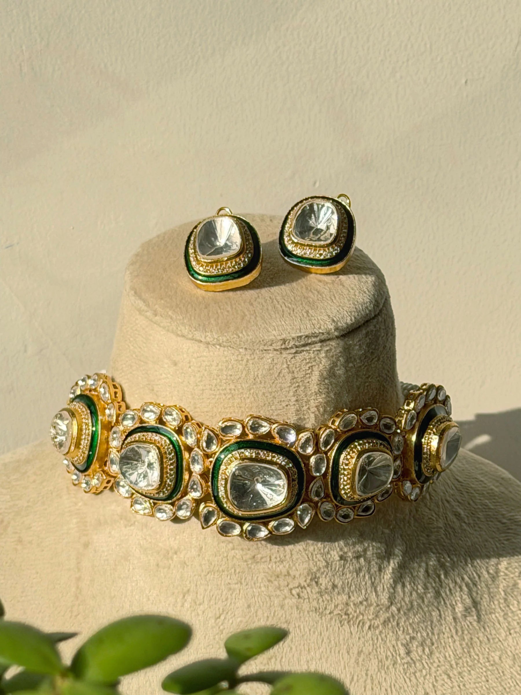 Traditional gold and green choker necklace with clear stones showcased with matching earrings
