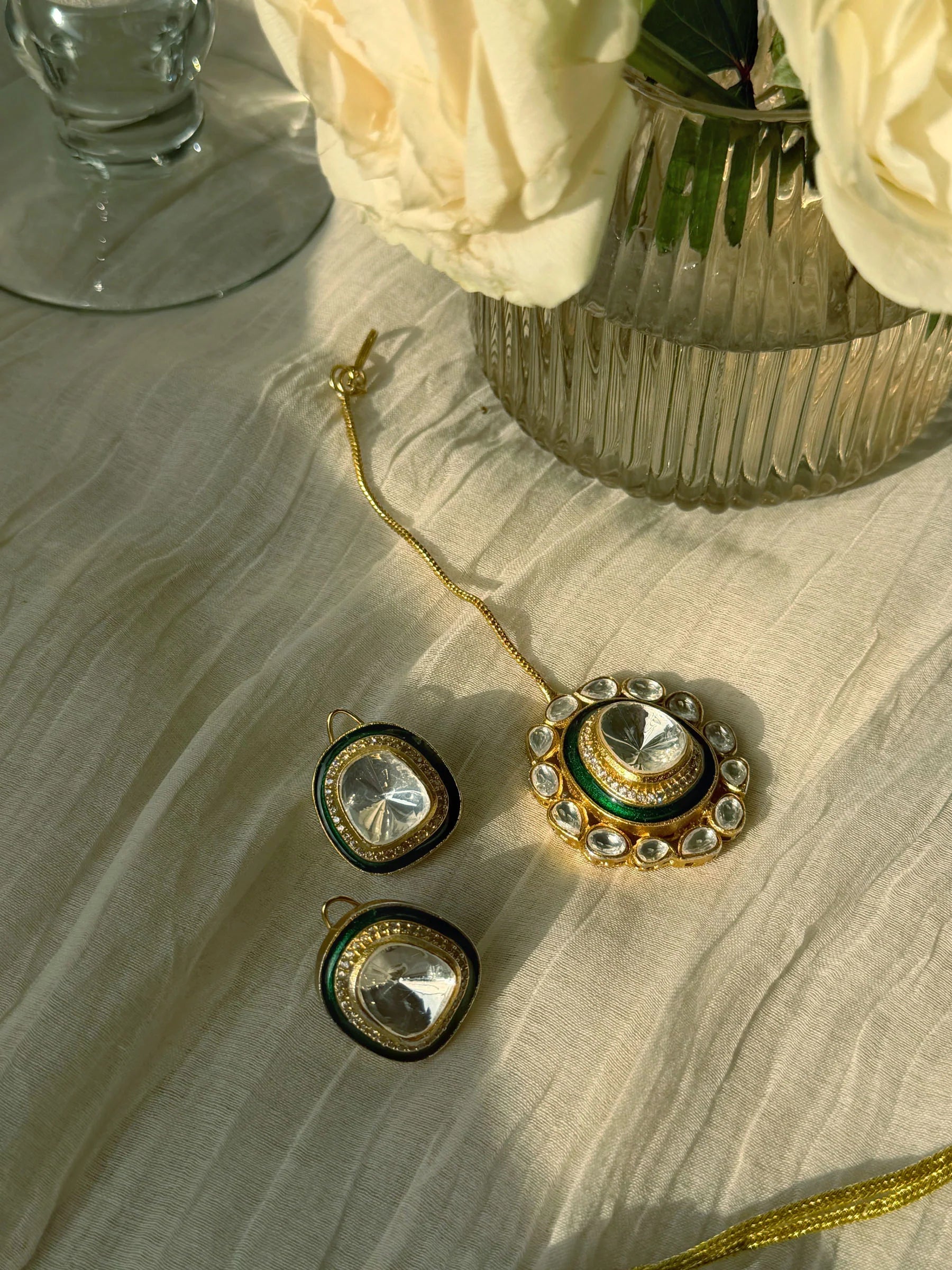 Close-up of ornate gold choker necklace with green enamel and crystal stones on display bust
