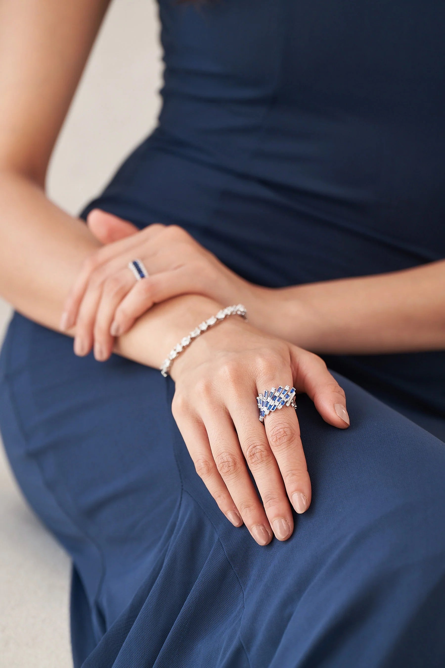 Elegant hand adorned with a fan-shaped ring featuring vivid blue baguette gemstones and shimmering diamond accents on a sleek band.
