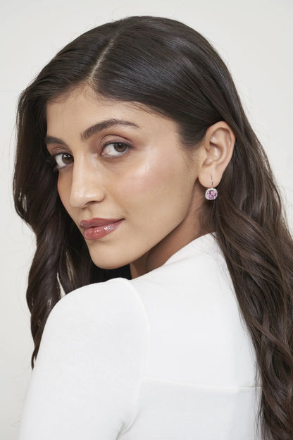 Elegant beauty shot featuring a delicate pink stone earring with a subtle drop design, styled on a woman with glowing skin.
