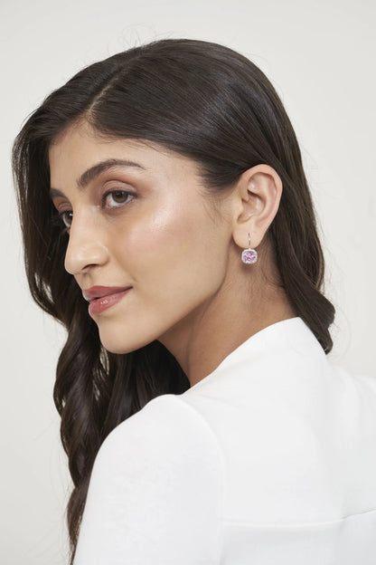 Minimalist fashion portrait focusing on a blush-toned drop earring that adds a gentle pop of color to a neutral look.
