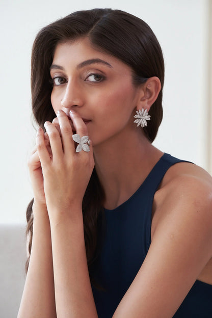 Elegant diamond statement ring in a floral design with pavé-set petals, showcased on fingers near the face.
