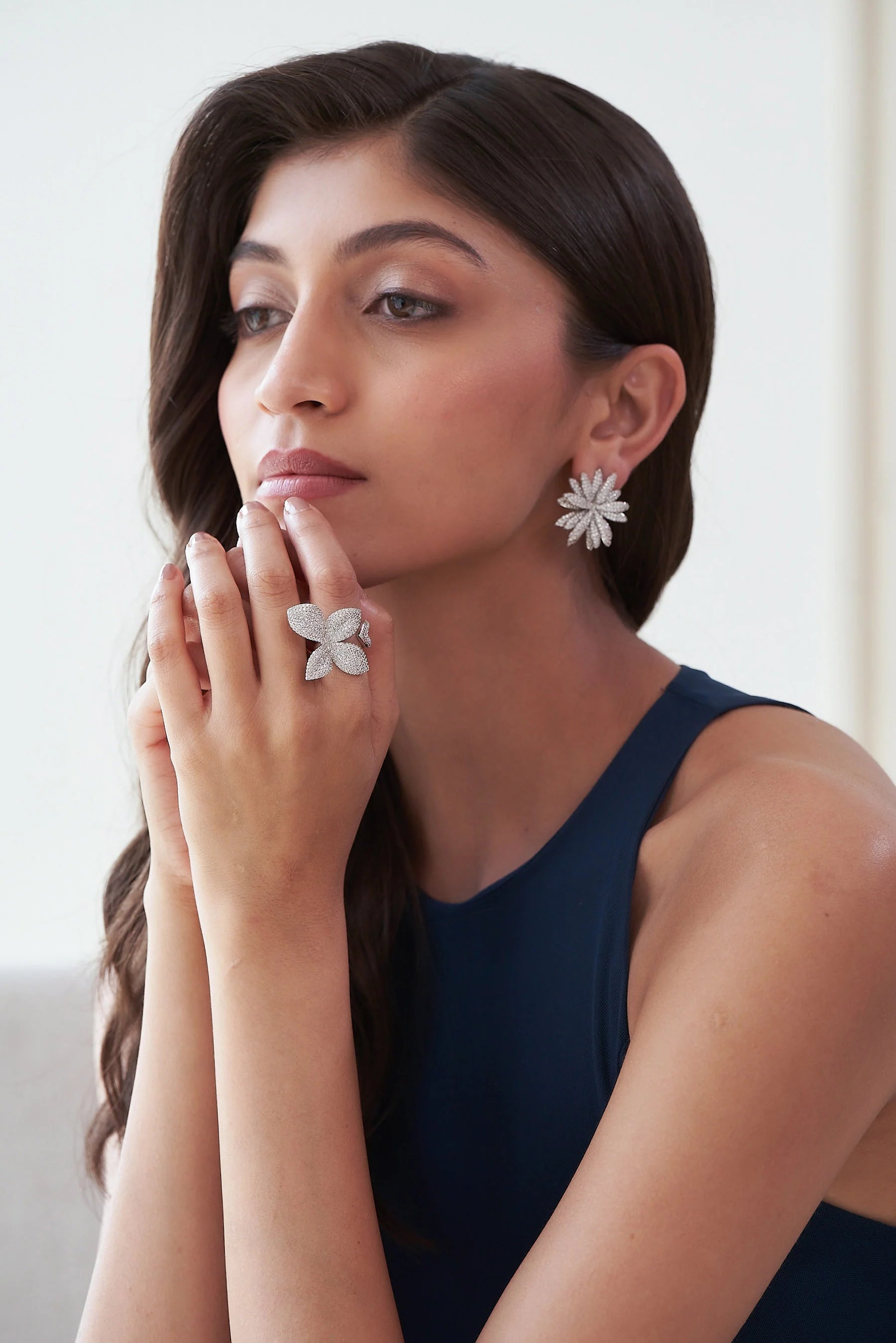 Fine jewelry flower ring featuring four shimmering diamond petals on a white gold band, worn on hand.
