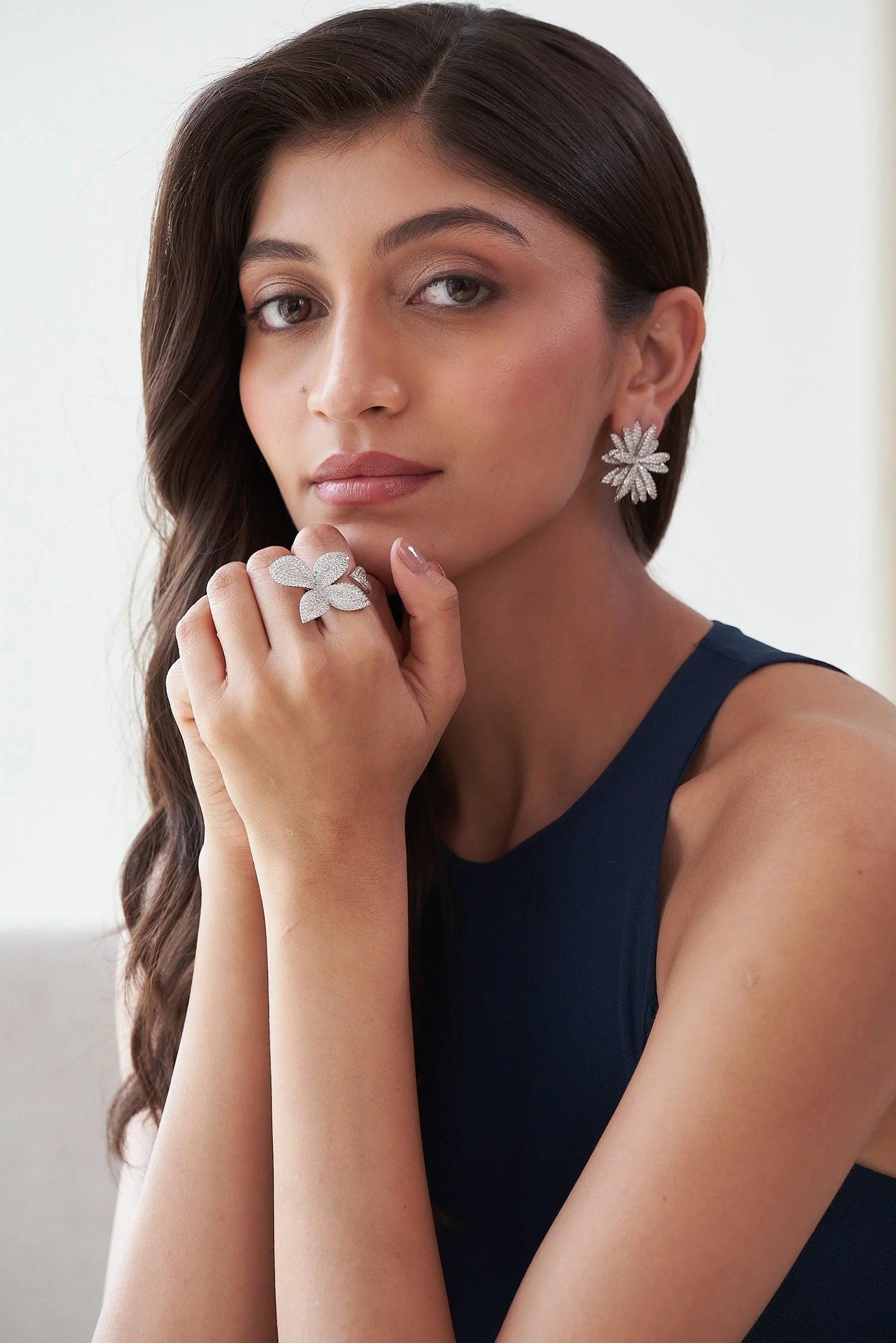 Luxury diamond ring shaped like a four-petal flower, encrusted with small stones and styled in a soft beauty shot.
