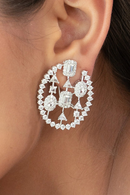 Close-up of a large geometric diamond earring with clustered stones and open circle structure, worn on ear.
