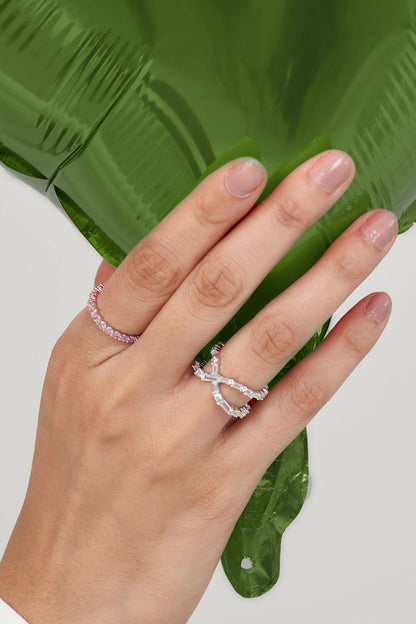 Elegant hand adorned with stacked diamond rings, gently placed against a glossy green leaf for a fresh, organic contrast.
