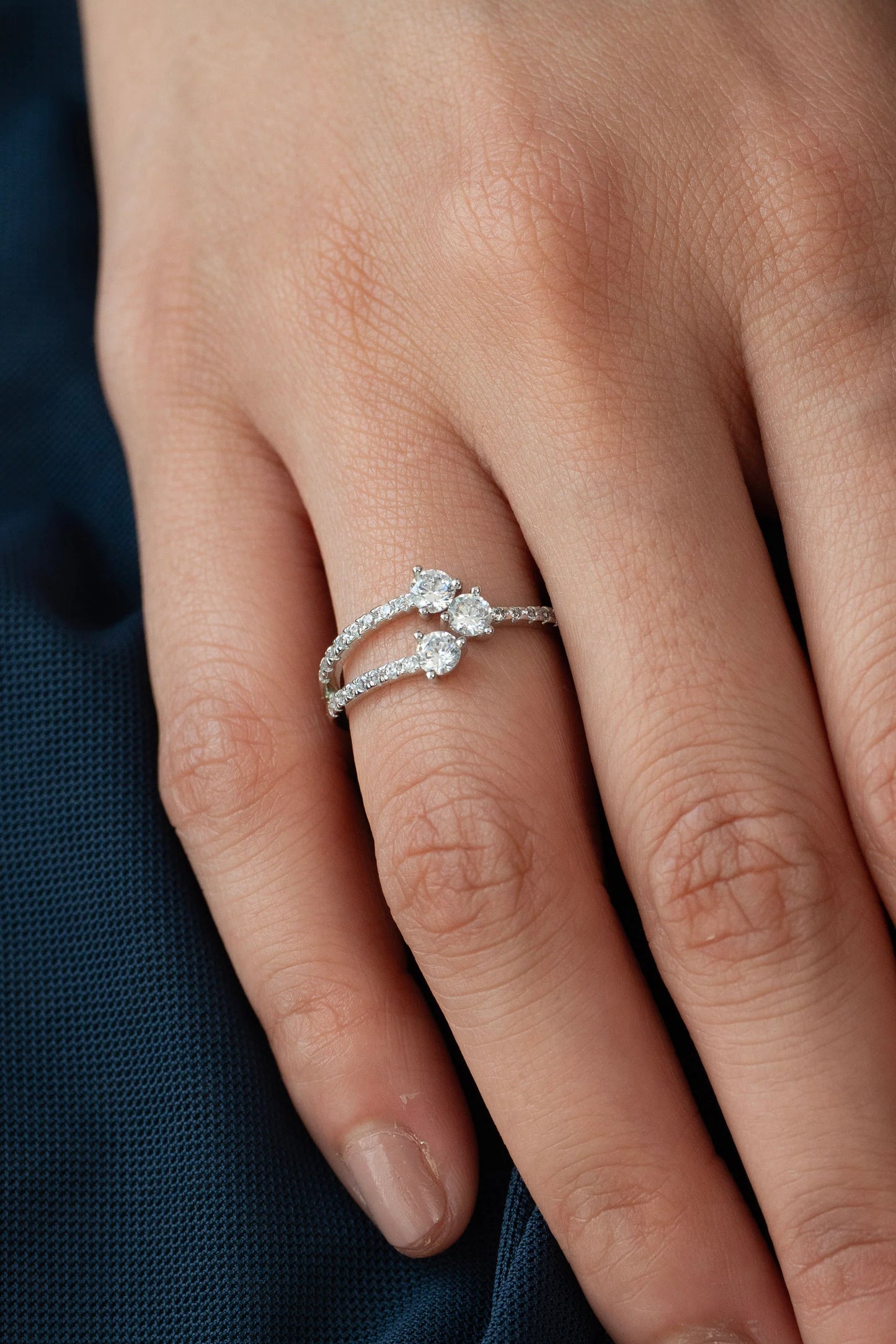 Close-up of a delicate diamond ring featuring two round solitaire stones on a split pavé band, elegantly set in white gold.
