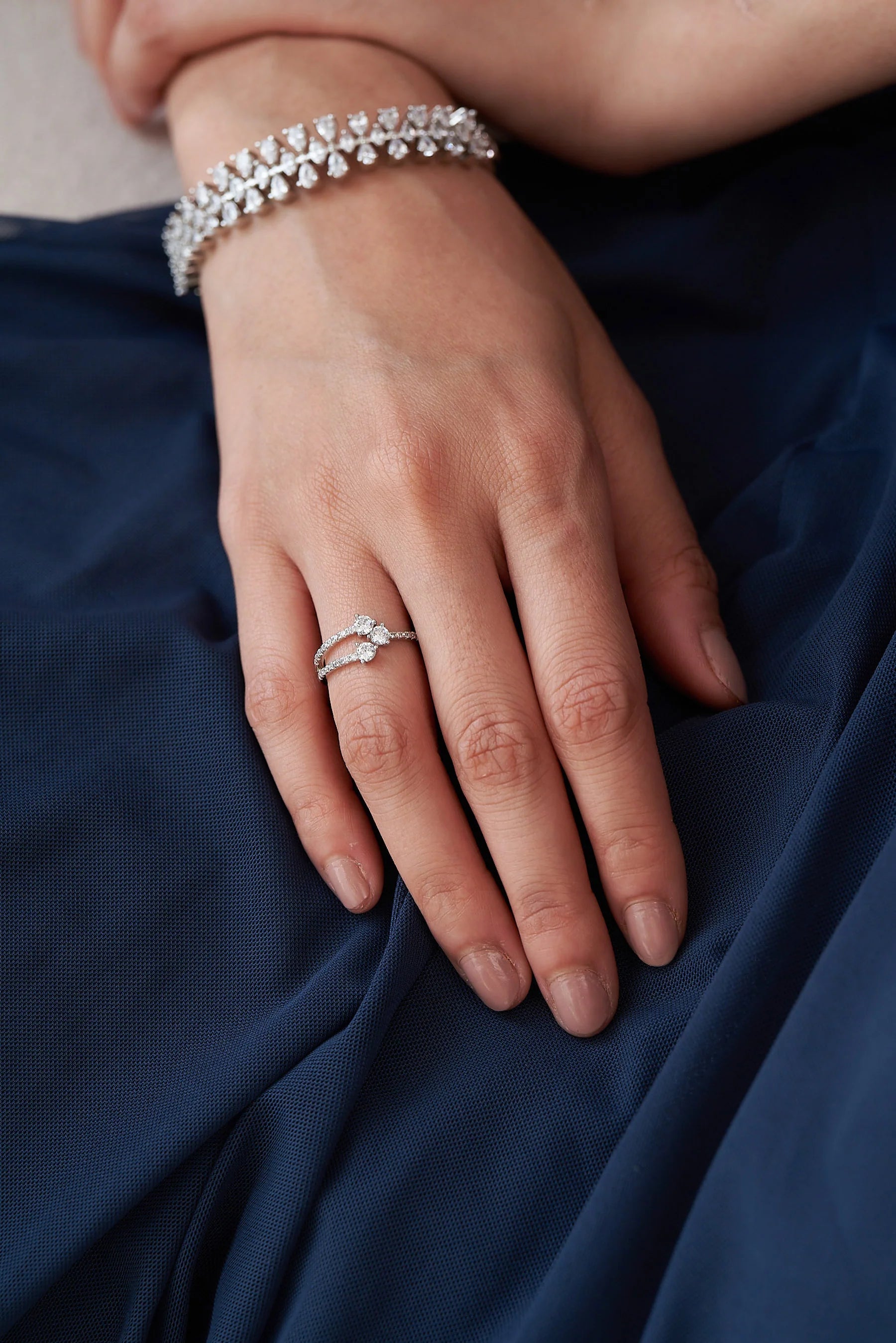 Elegant open-style diamond ring with twin round-cut stones and a slim band lined with shimmering pavé diamonds.
