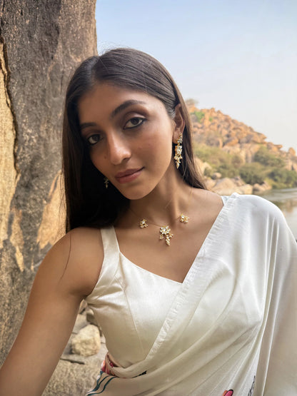 Minimalist jewelry shot focusing on a thin gold necklace with spaced charm accents and matching detailed earrings.

