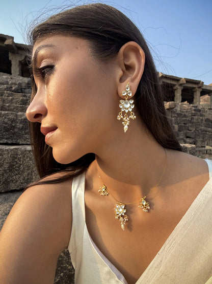 Luxury styling image capturing a woman in a blue outfit wearing a dainty gold necklace with multiple small pendants.
