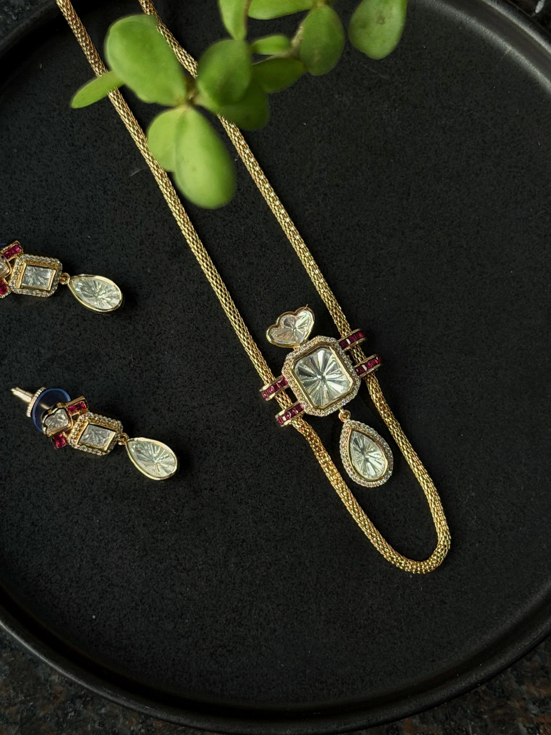 Elegant gold jewelry set with crystal pendant necklace and matching drop earrings with ruby details
