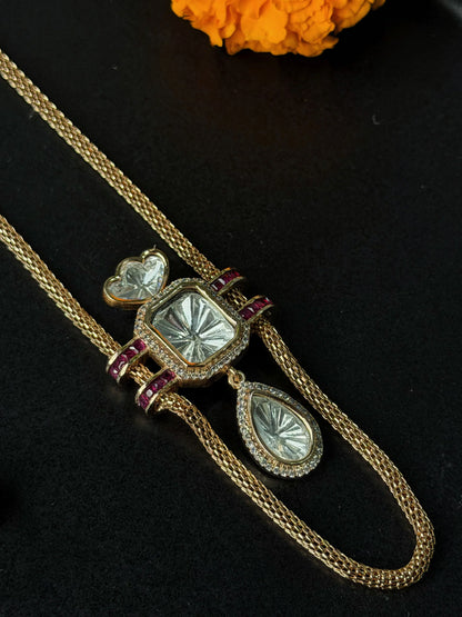 Premium gold chain necklace with geometric crystal pendant and coordinating earrings on black surface
