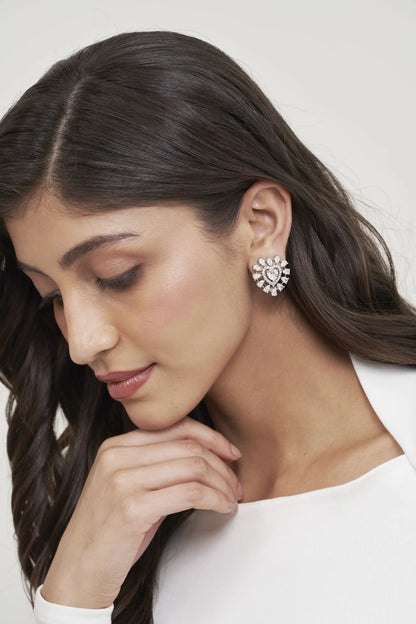 Close-up of a woman wearing a heart-shaped diamond stud earring with a radiant halo design, styled in an elegant beauty shot.
