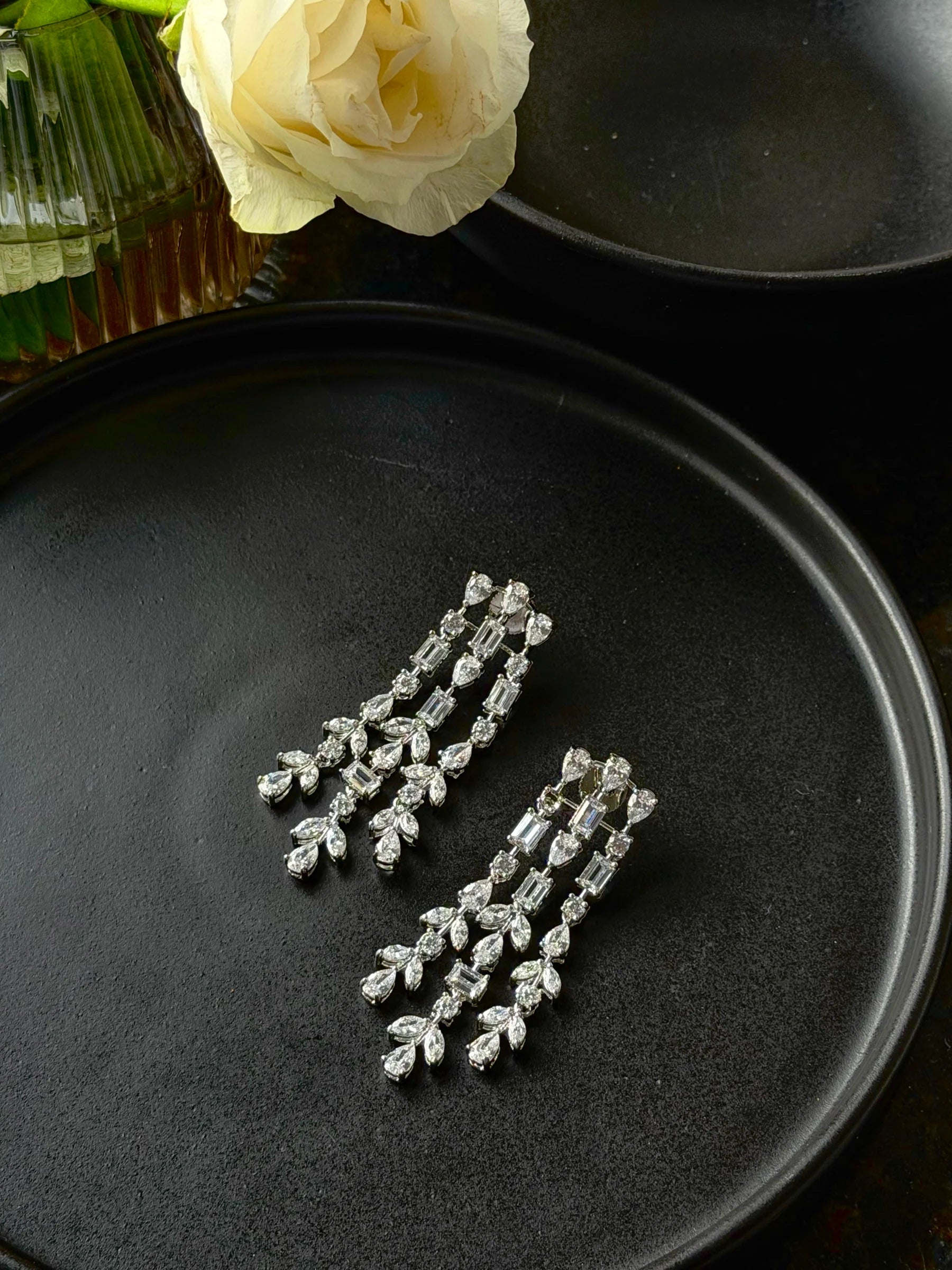 Elegant silver chandelier earrings with cascading crystal stones on dark background
