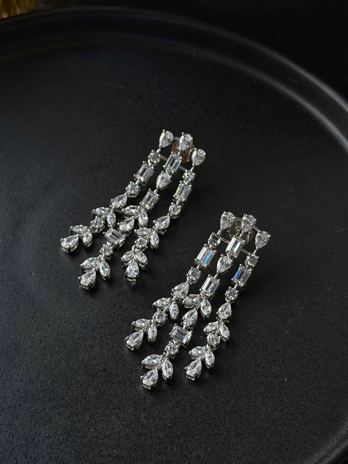 Luxury long drop earrings with baguette and pear-shaped crystals in detailed close-up
