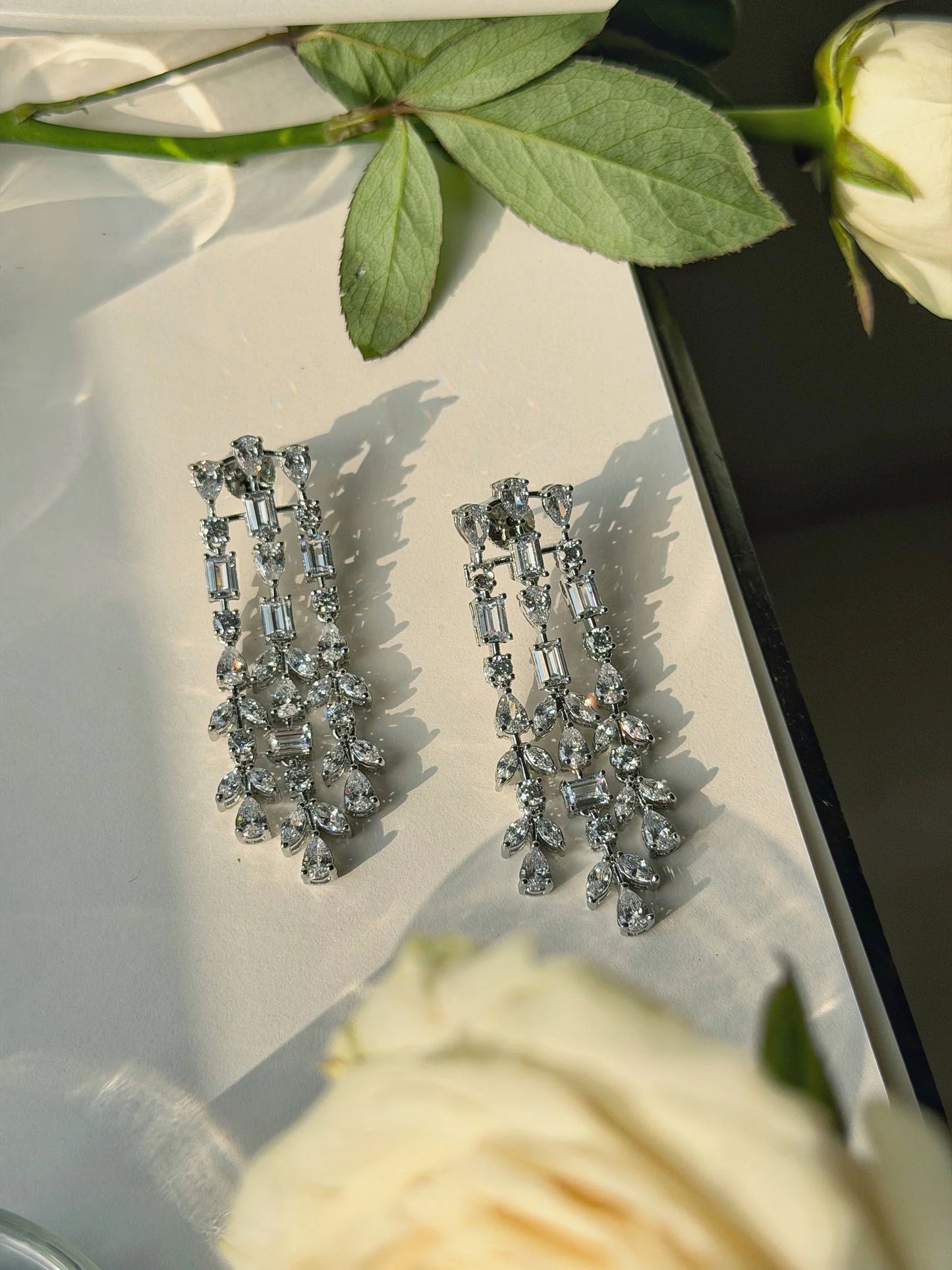 Statement silver earrings with layered crystal design and sparkling drop elements

