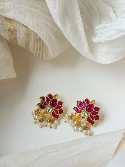 Elegant gold drop earrings with red enamel and crystal detailing on soft neutral background
