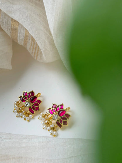Stylish gold earrings with round motif, red enamel, and crystal accents in soft lighting
