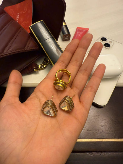 Premium gold ring and statement earrings with clear stones displayed on hand in indoor lighting
