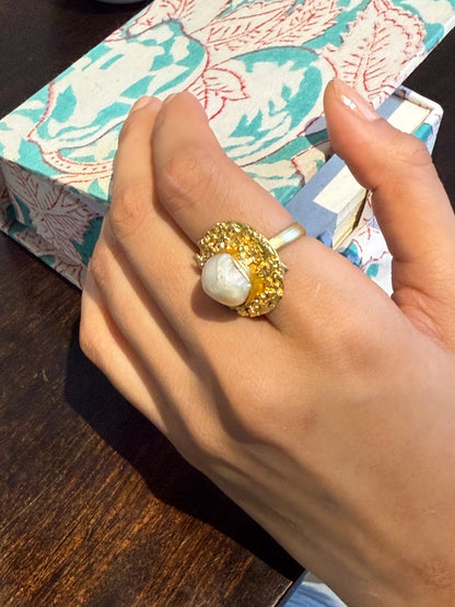 Fashion jewelry shot of bold gold pearl ring on hand with minimal lifestyle background
