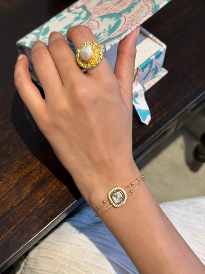 Premium jewelry close-up of gold ring with pearl centerpiece on hand holding cup
