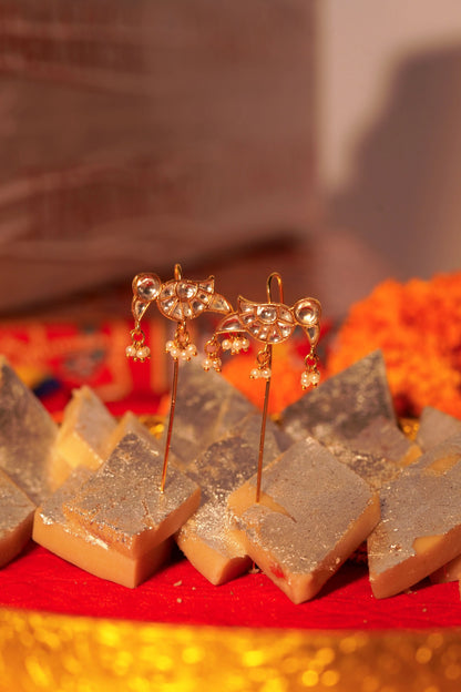 Luxury gold earrings with crystal detailing and pearl drops styled on Indian mithai for festive jewelry shoot
