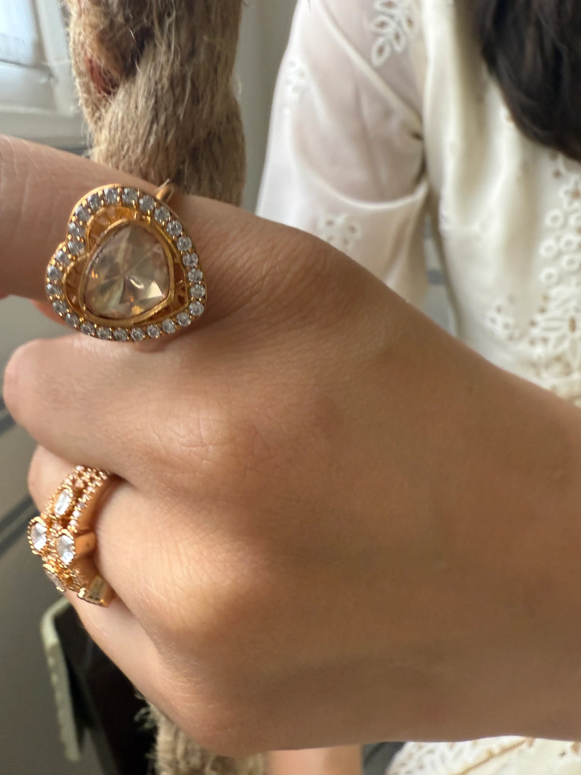 Elegant gold ring with heart-shaped gemstone and pavé diamonds on woman’s hand

