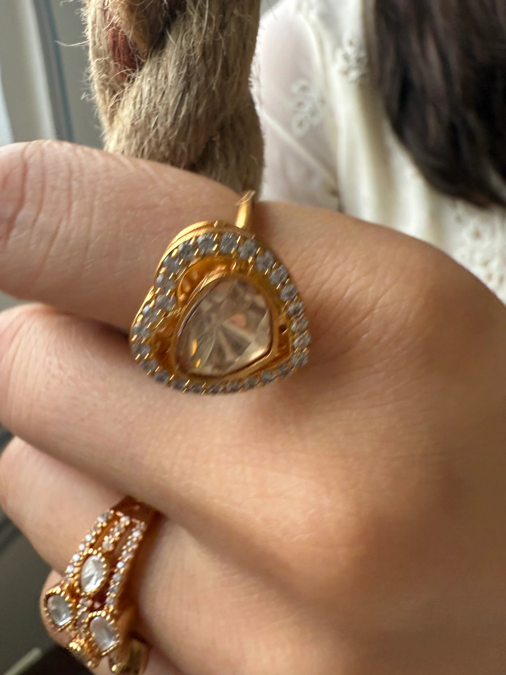 Fashion jewelry close-up of heart-shaped gold ring with diamond detailing on fingers
