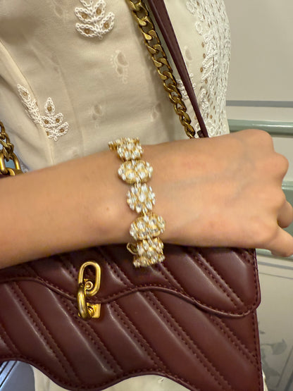 Luxury jewelry close-up featuring gold bracelet with white stones and quilted leather purse
