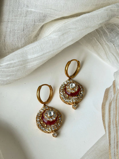 Luxury gold hoop earrings with red enamel detailing and sparkling crystal accents in minimal jewelry styling
