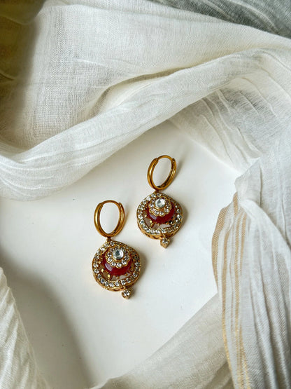 Luxury gold hoop earrings with red enamel detailing and sparkling crystal accents in minimal jewelry styling
