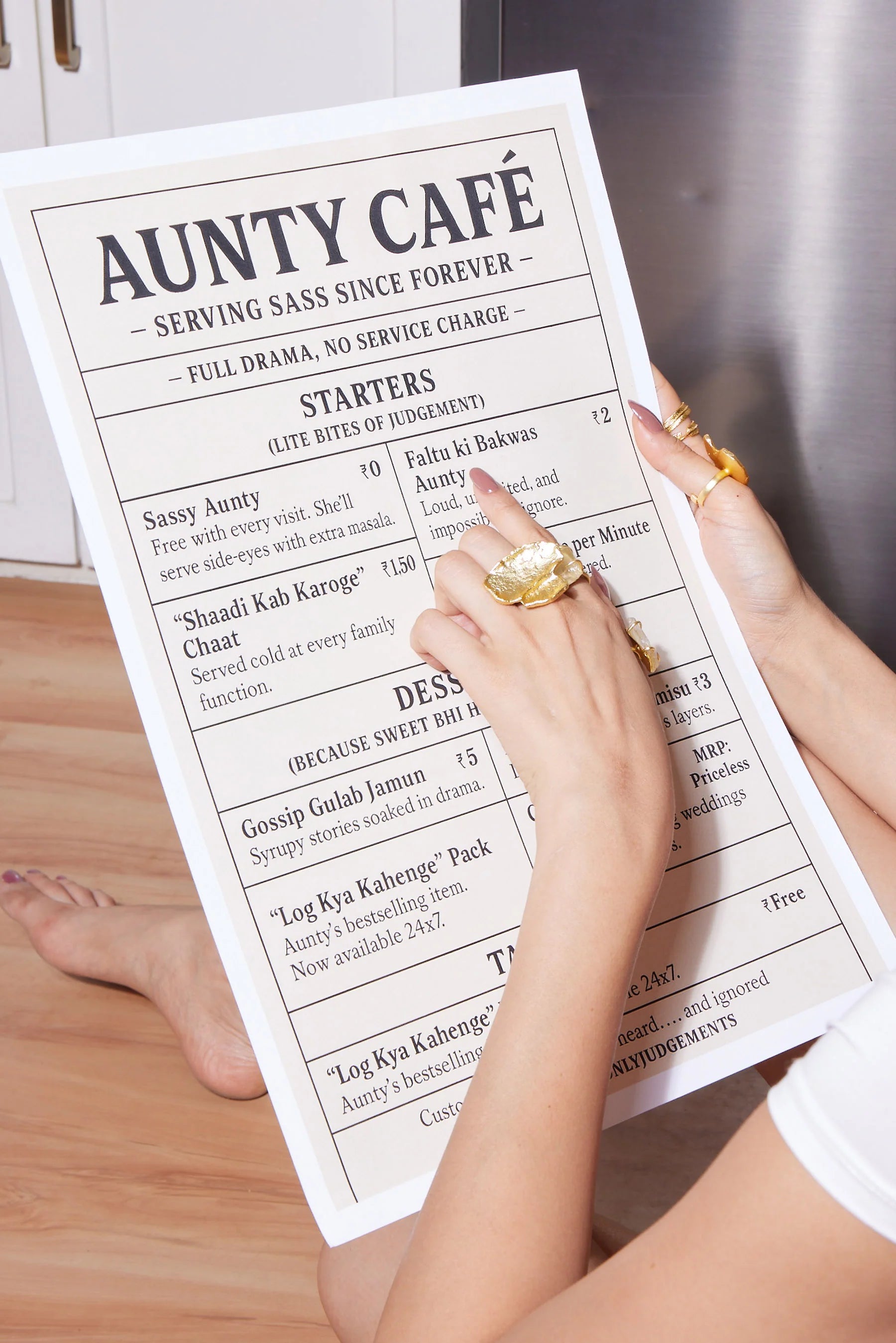 Woman’s hands with gold rings pointing at a playful restaurant menu with humorous dish names
